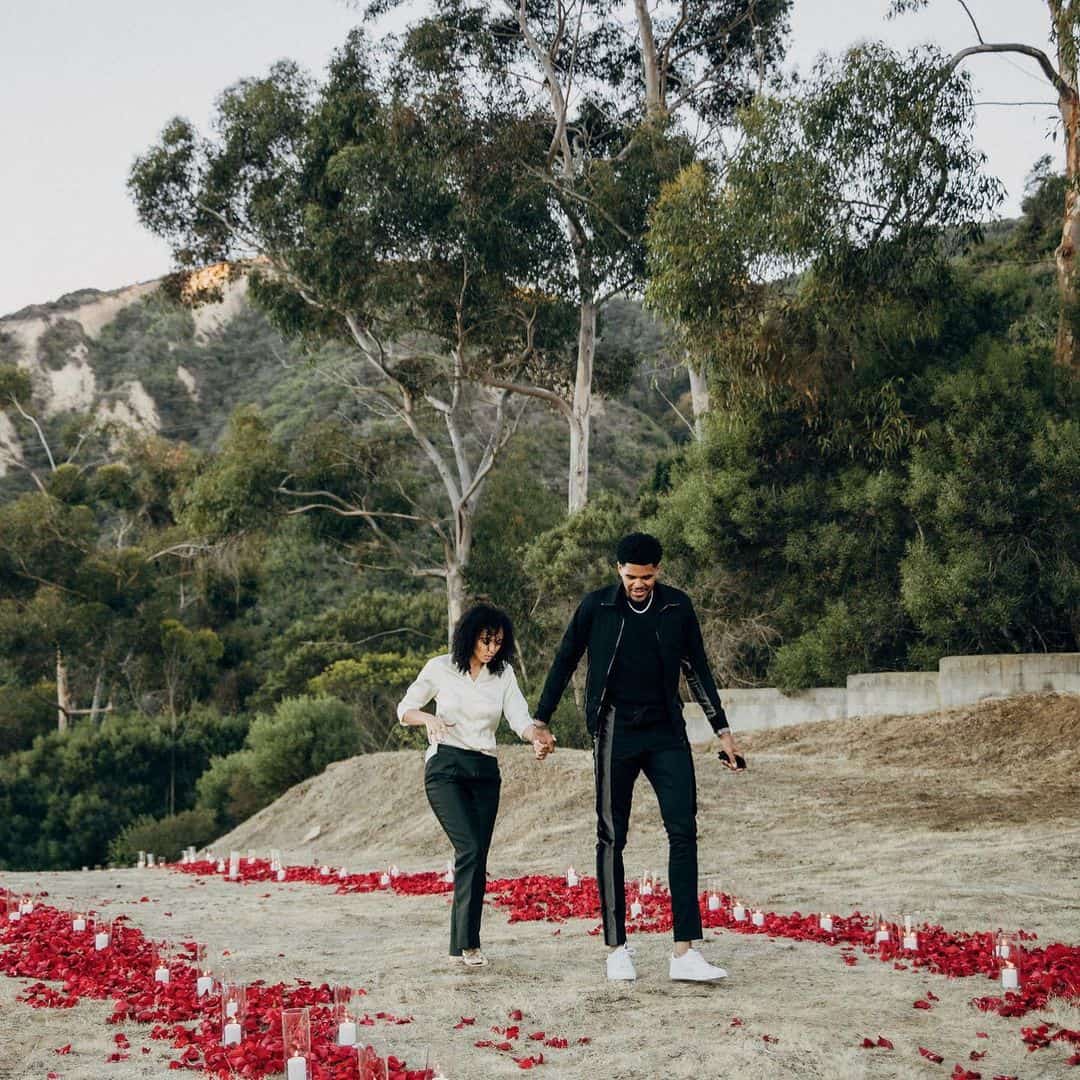 Jasmine Winton and Tobias Harris from his Instagram: "“Life exists only at this very moment, and in this moment it is infinite and eternal. For the present moment is infinitely small; before we can measure it, it has gone, and yet it persists forever.” SHE SAID ”YES, YES!” ❤️💍🖤"